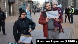 Мариана (с черното яке). На плаката, който държи, пише "Уважаеми управляващи, принуждавате родители да даряват бебешки обувки. Никога неносени".