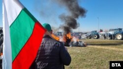 Протестиращ земеделски производител при село Труд на фона на горяща бала със сено