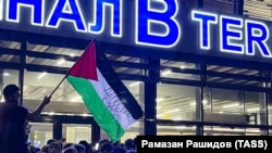 Местен гражданин развява палестинско знаме с надпис "Дагестан е с вас" по време на пропалестински митинг на летището в Махачкала