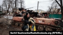 Жителката на Буча Олха разказва пред RFE/RL: "Когато баща ми построи къщата ни, той направи мазе отдолу и ни каза: "Ако нещо се случи, това е вашето бомбоубежище". "Когато [инвазията] се случи, погледнахме навън и видяхме танкове, които вече стреляха в двора ни. Втурнахме се към мазето и седяхме там в продължение на седем часа. Танковите вериги изскърцаха и се разрази ужасна битка", спомня си тя. Два танка са се прикрили зад къщата ѝ. Тогава, казва Олха, "вече се бяхме сбогували с живота.... Тогава излязохме и видяхме тази ужасяваща картина. Като някакъв Армагедон".