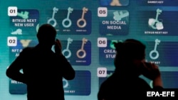 Потребители пред екран в Тайланд пред екран, на който се представят промоции, свързани с дигитални валути