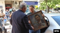 Алекбер Абил от младежката структура на ДПС-Доган държи портрет на почетния лидер на движението Ахмед Доган. Това се случва, докато служители на областната администрация в София запечатват партийната централа на ДПС, 19 май 2025 г.