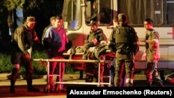 Ранените бойци пристигат в Новоазовск, придружавани от про-руски военни.