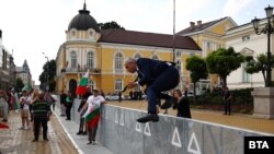 Лидерът на "Възраждане" Костадин Костадинов прескача загражденията около сградата на парламента, за да се присъедини към симпатизантите си.