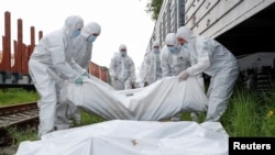 Украински работници носят телата на руски войници, убити по време на инвазията, към хладилен вагон, за да бъдат откарани в Киев.