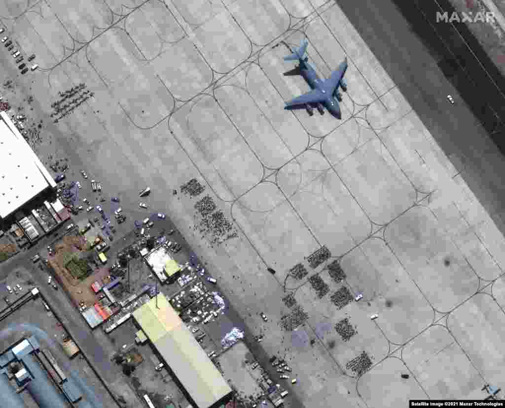 Големи групи от хора чакат на асфалта на международното летище &quot;Хамид Карзай&quot; в Кабул. На снимката се вижда и транспортен самолет С-17, готов за излитане на 23 август.