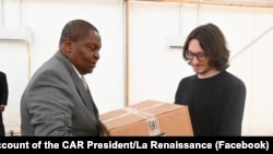 На снимка, публикувана на страницата във Фейсбук на президента на ЦАР, Дмитрий Ситий (вдясно) предава кутии с медицински консумативи на президента Фостен-Арканж Туадера