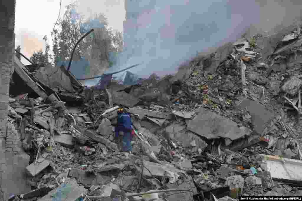 Спасител претърсва тлеещите развалини на срутена сграда в Киев. Някои от жителите на сградата все още са в неизвестност.