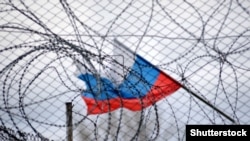 Руско знаме се развява зад ограда и бодлива тел.