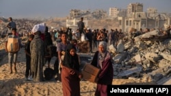 Жени носят чували и кутии с храна и хуманитарна помощ, разтоварени от конвой на Световната хранителна програма в Газа, 16 юни 2025 г.