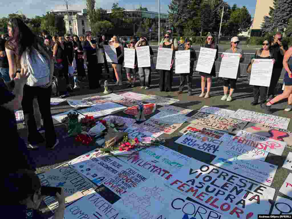 Протестиращите показват плакати, с които осъждат насилието срещу жени, и полагат цветя в памет на Теодора Марку.