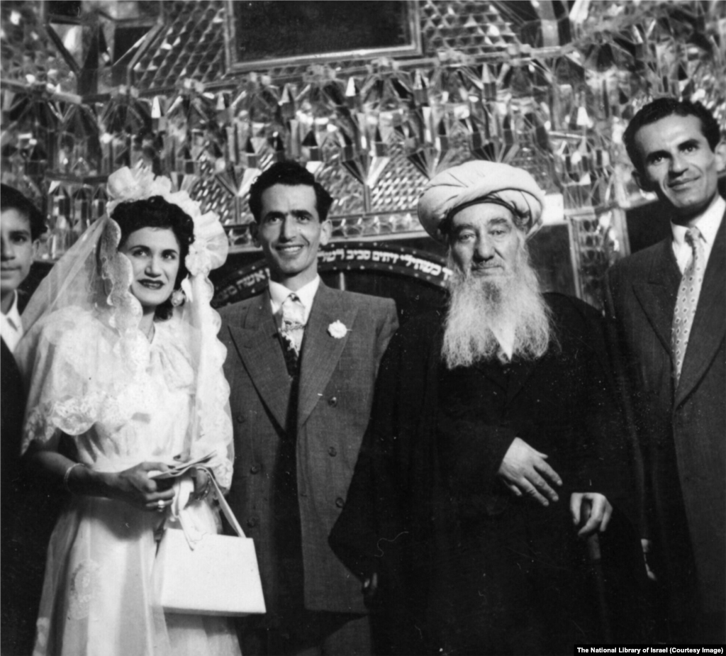 Еврейска сватба в Иран през 50-те години на миналия век. Церемонията се води от равин Шломо Коен Цедек (в центъра вдясно), главен равин на страната. Надписът на еврейския език зад групата препраща към библейския стих: „Жена ти ще бъде като плодоносна лоза в дома ти; децата ти ще бъдат като маслинени филизи около трапезата ти“.