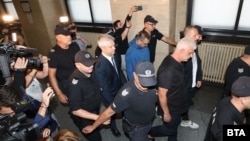 Кметът на Варна Благомир Коцев (в средата с вратовръзката) е конвоиран заедно с останалите трима задържани по делото му в Софийския градски съд, 11 юли 2025 г.