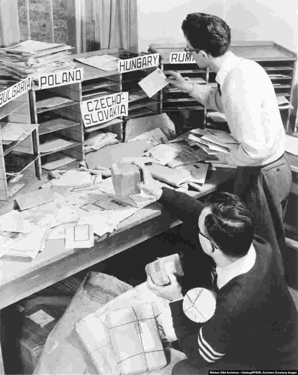 Служители на RFE в централата в Мюнхен сортират пощата, получена от различни държави, в които има излъчвания.RFE е основана с цел „да запази жив духа на свободата в сърцата и умовете на пленените хора“, които живят в комунистическите режими на Източна Европа.