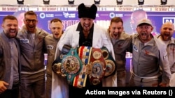 Украинският боксьор в тежка категория Олександър Усик позира със своите колани на пресконференция на лондонския стадион "Уембли" дни преди мача му с британеца Даниел Дюбоа. При първата им битка, на 26 август 2023 г., украинецът спечели с нокаут в деветия рунд.