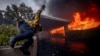 Пожарникар прескача ограда на фона на разрастващия се пожар в Лос Анджелис. Снимката е от 7 януари.