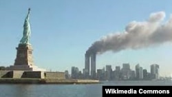 Ню Йорк, 11 септември 2001 г. Двете кули-близнаци на Световния търговски център горят, след като в тях се врязват самолети, управлявани от атентатори. На преден план е Статуята на свободата.