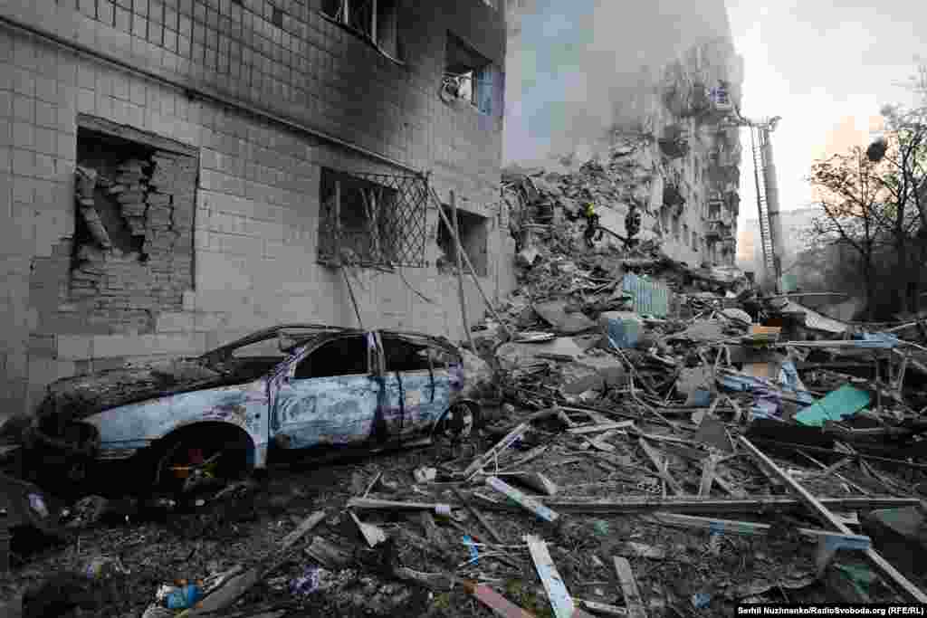 Изгоряла кола до срутената част на жилищна сграда в Киев.Русия отрича, че армията ѝ извършва целенасочени атаки срещу гражданска инфраструктура
