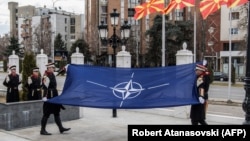 Македонски войници издигат знамето на НАТО по време на официална церемония пред сградата на правителството в Скопие на 12 февруари