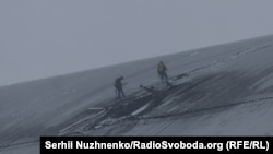 Служители инспектират дупката в покрива на защитния корпус, оставена след атаката с дрон на 14 февруари 2025 г.
